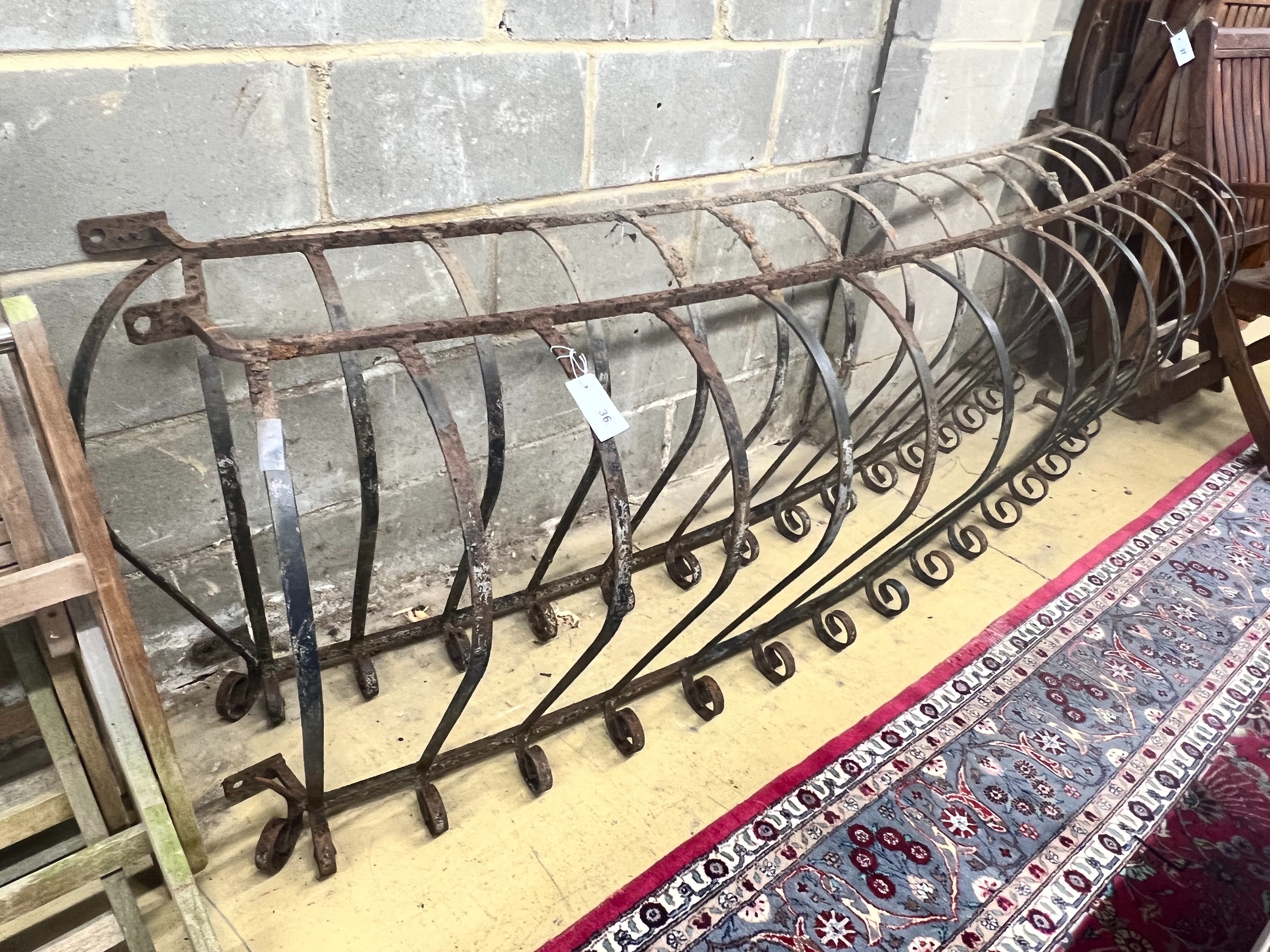 A pair of wrought iron bowed balcony rails, larger width 234cm height 73cm